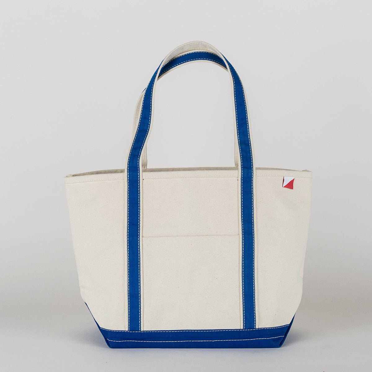 Natural canvas tote bag with royal blue straps, trim and base, shown from the front.