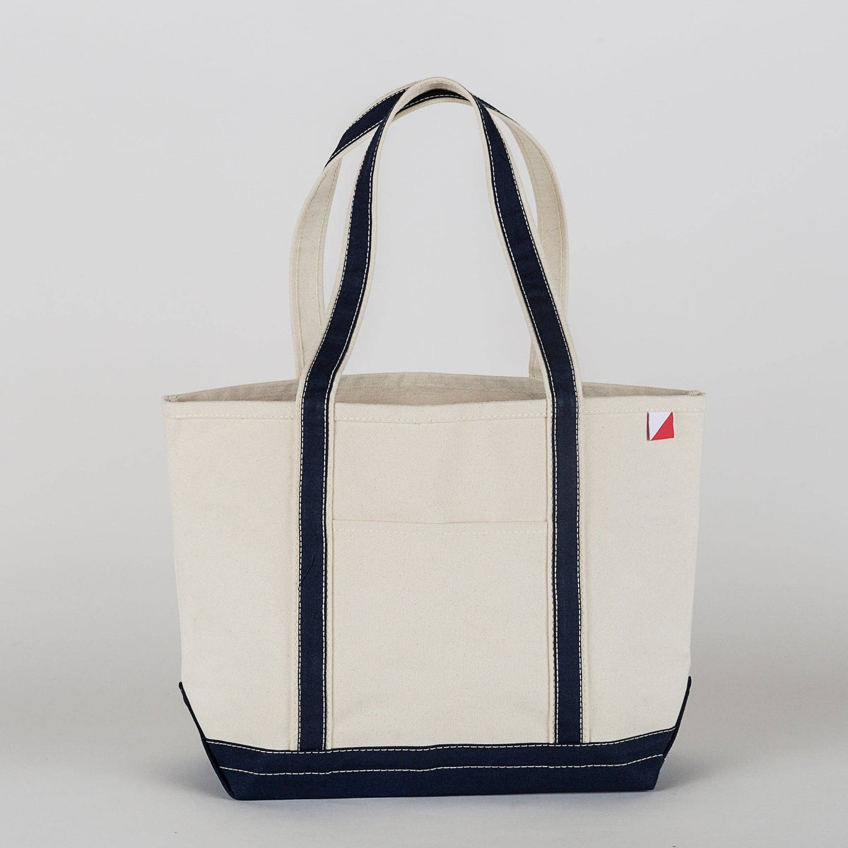 Natural canvas tote with navy straps, trim, and base, shown from the front