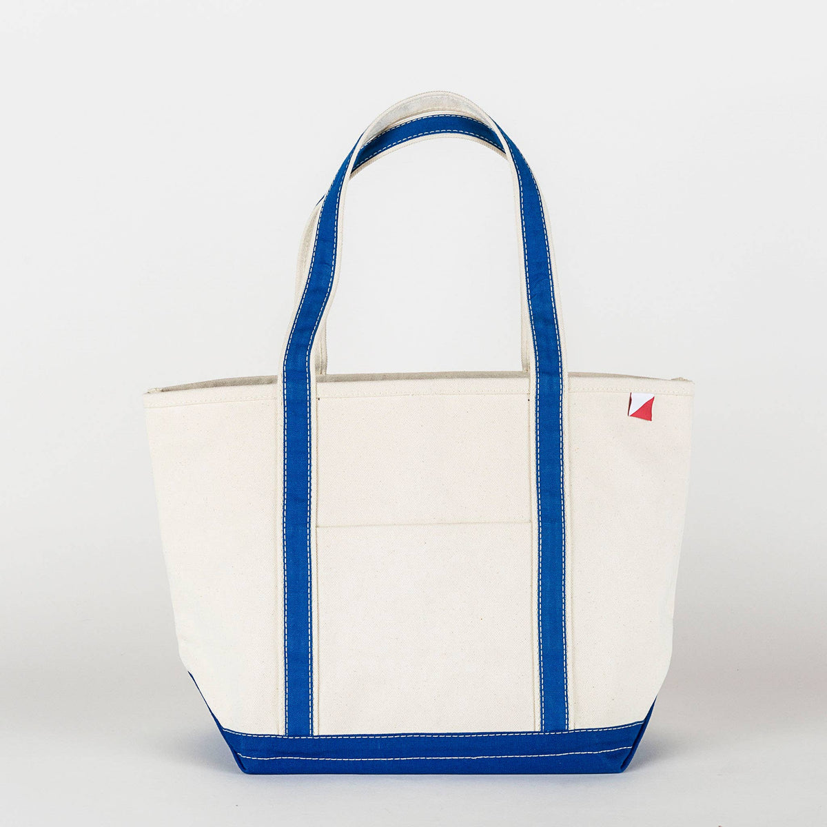 Woman carrying the natural canvas tote with red straps and base at a marina