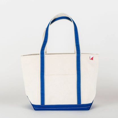 Woman carrying the natural canvas tote with red straps and base at a marina