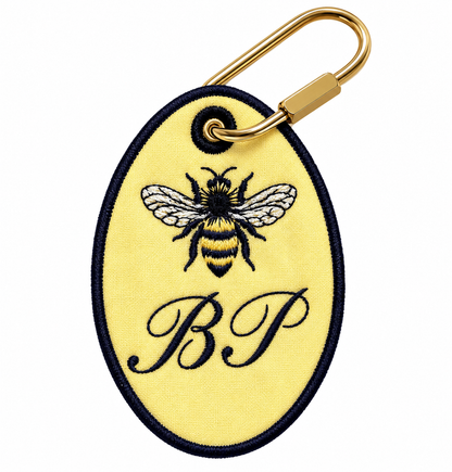 White squiggle-shaped embroidered keychain with a blue border, a soccer ball, and a VM monogram