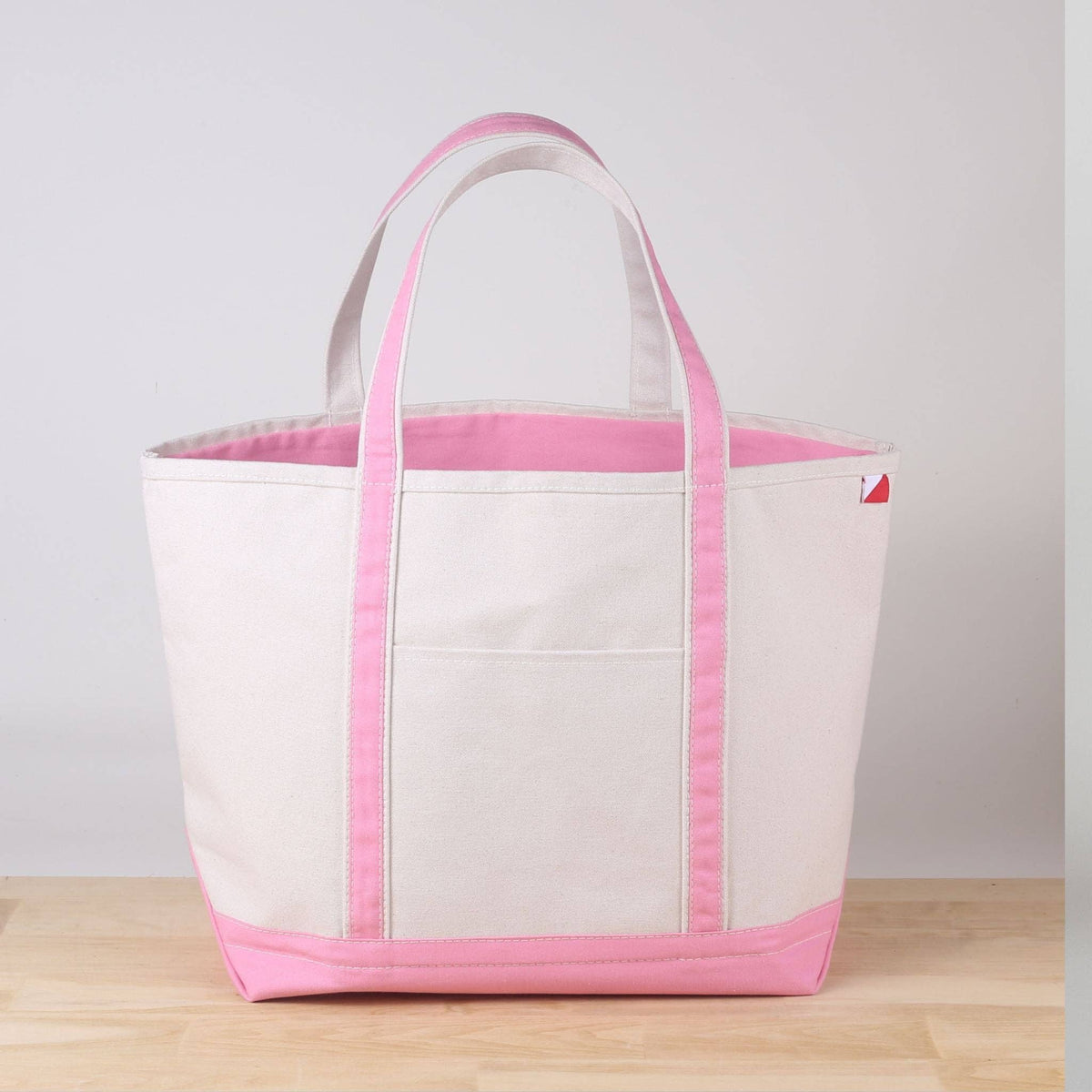 Large natural canvas tote with light pink handles, pink trim, and a pink bottom