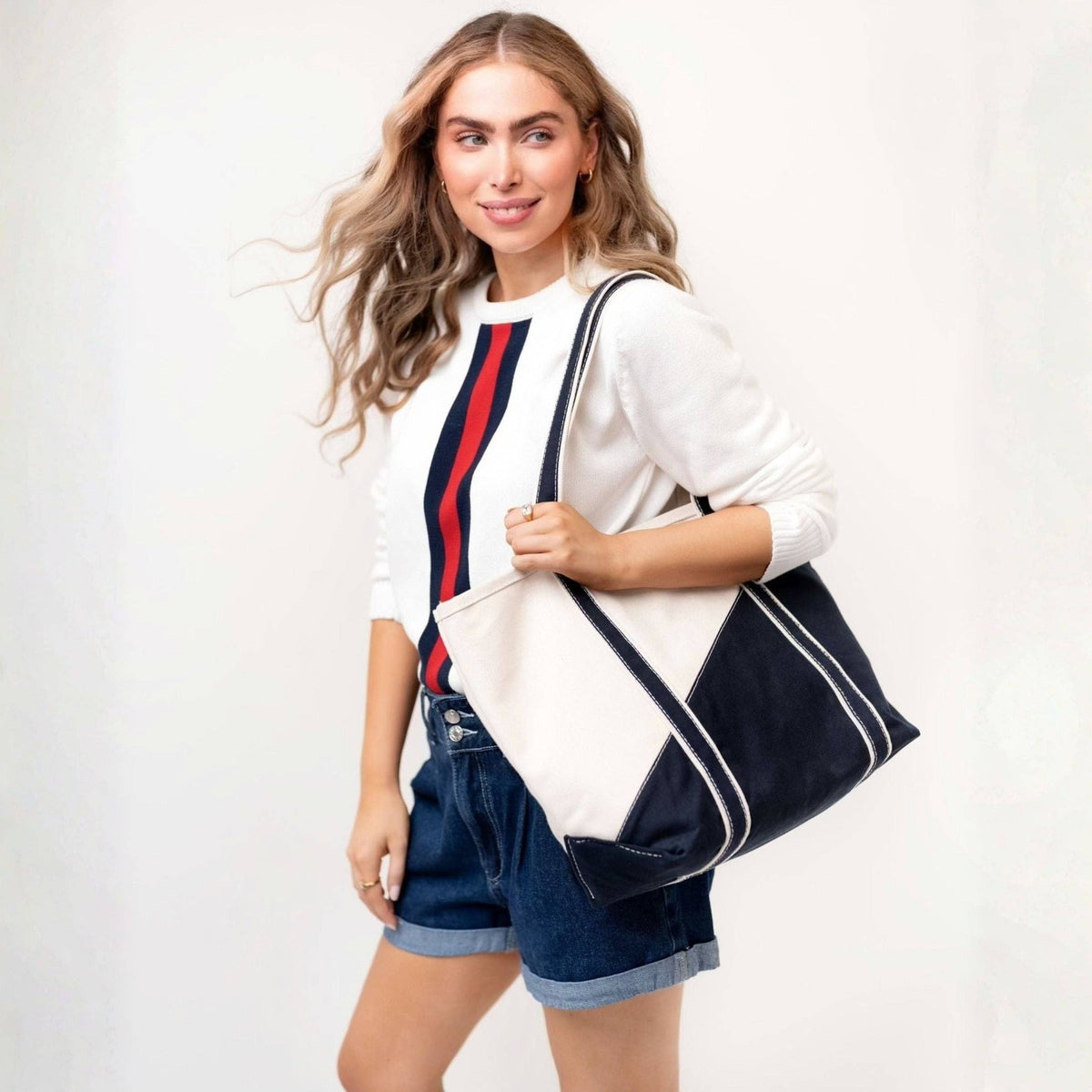 Woman carrying the natural and navy canvas tote over her shoulder