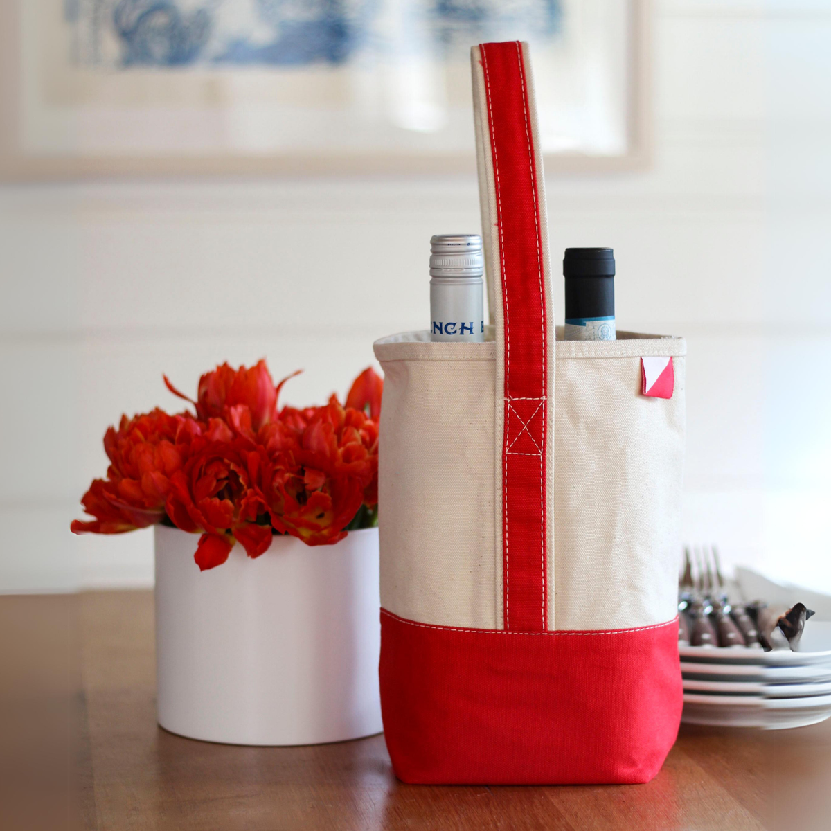 Natural canvas wine gift bag with a red handle and red base holding two bottles of wine