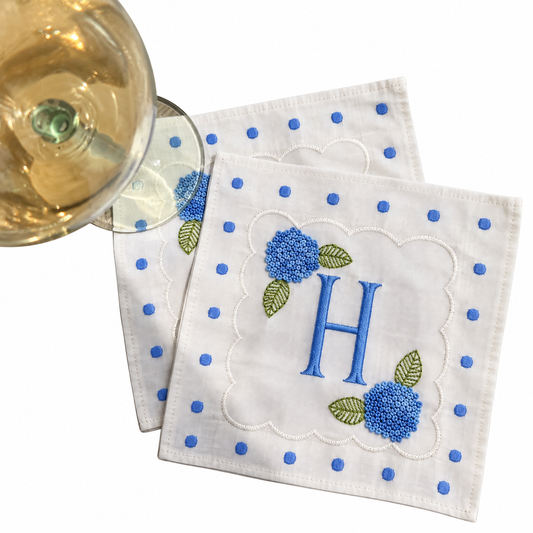 White linen cocktail napkins with a blue polka dot border, scalloped frame, blue H monogram, and embroidered hydrangeas