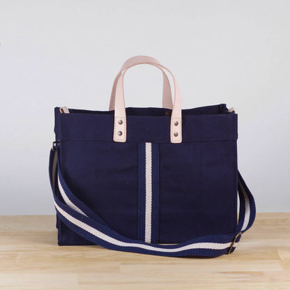 Mini navy canvas box tote with leather handles, a white center stripe, and a navy and white striped detachable strap