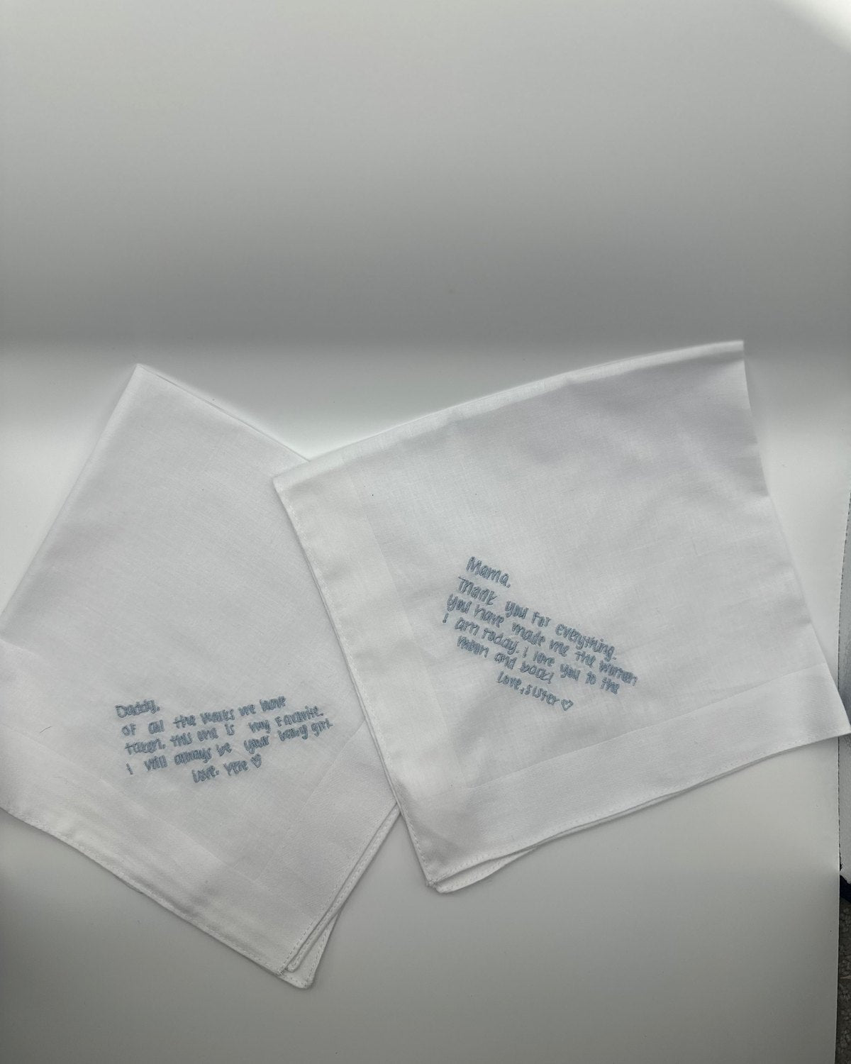 Two white handkerchiefs embroidered with a handwritten message